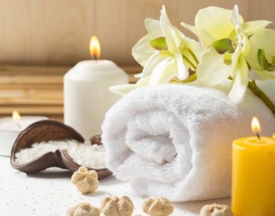 Spa setting with rolled towel, candles and orchids
